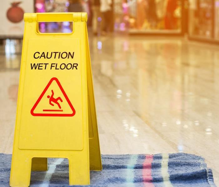 A caution sign on the floor near a water leak.