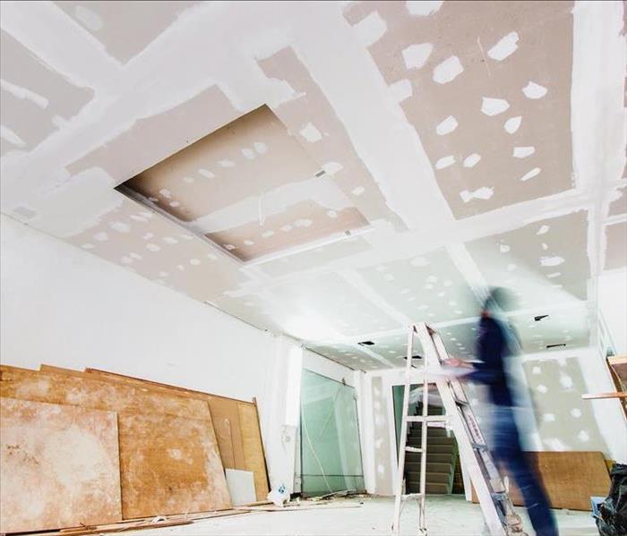A worker installs drywall in a construction project.