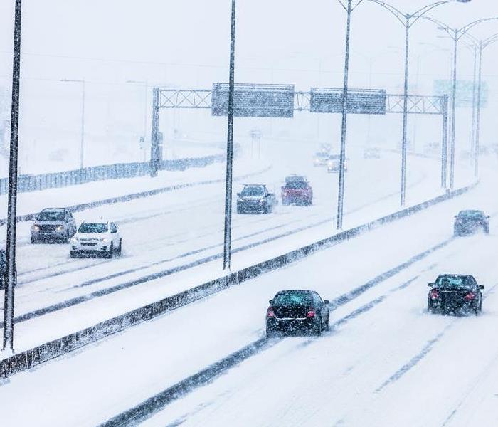 Cars drive down a snowy highway.